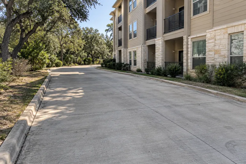 Shaded concrete drive lane running past an apartment building