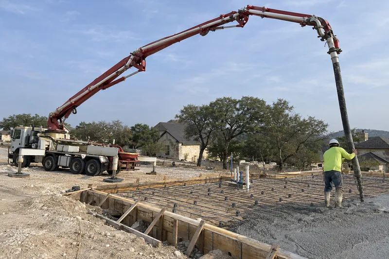 Boom pump arm reaching over forms to place concrete