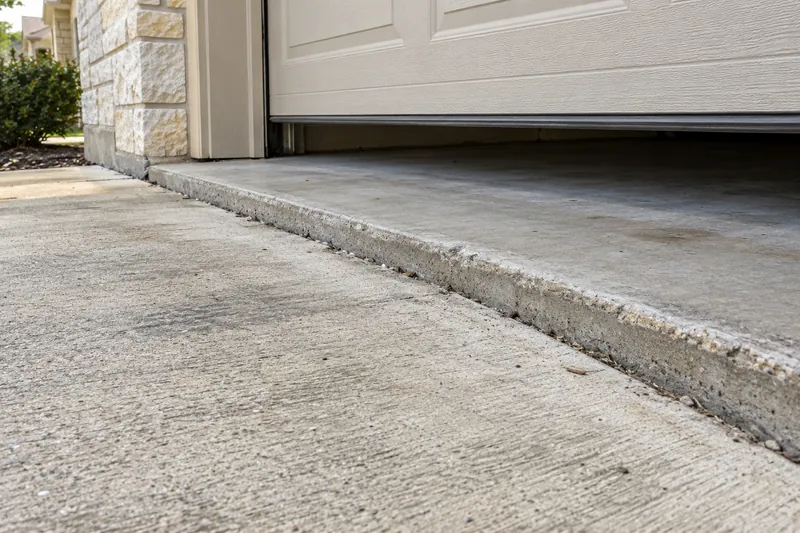 Driveway slab sunk below the garage floor at the door