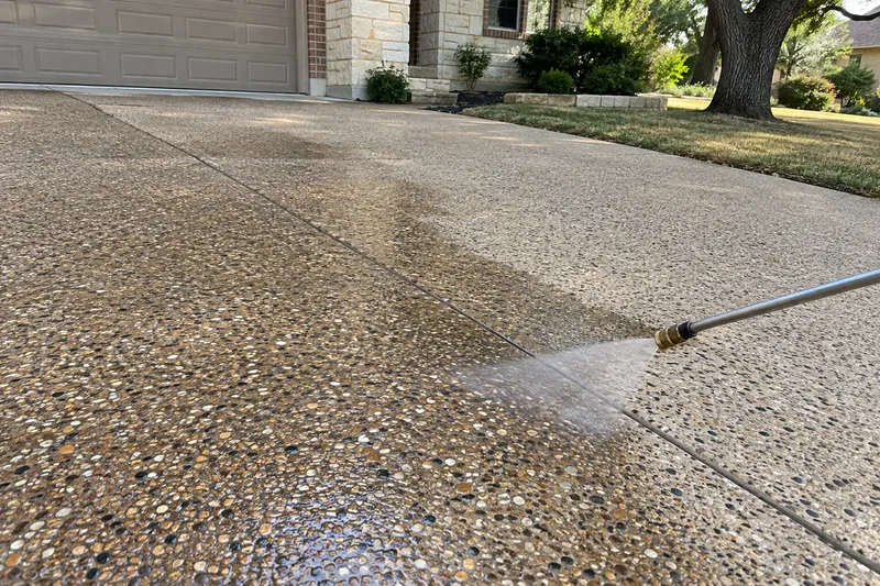 Sprayer wetting an exposed-aggregate driveway with clear sealer
