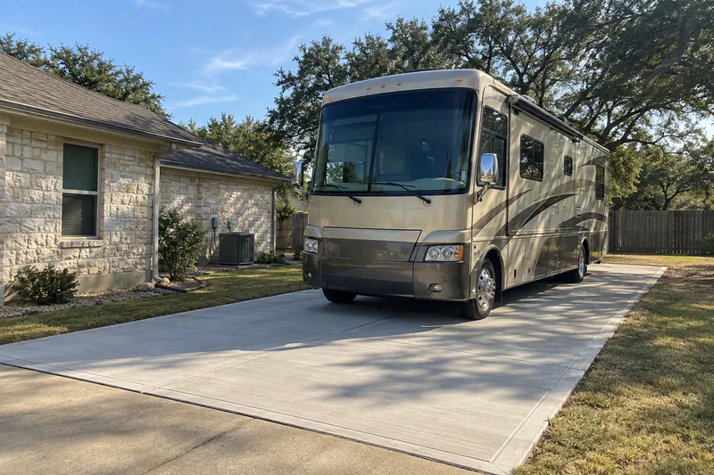 Motorhome parked on a new concrete pad beside a stone house