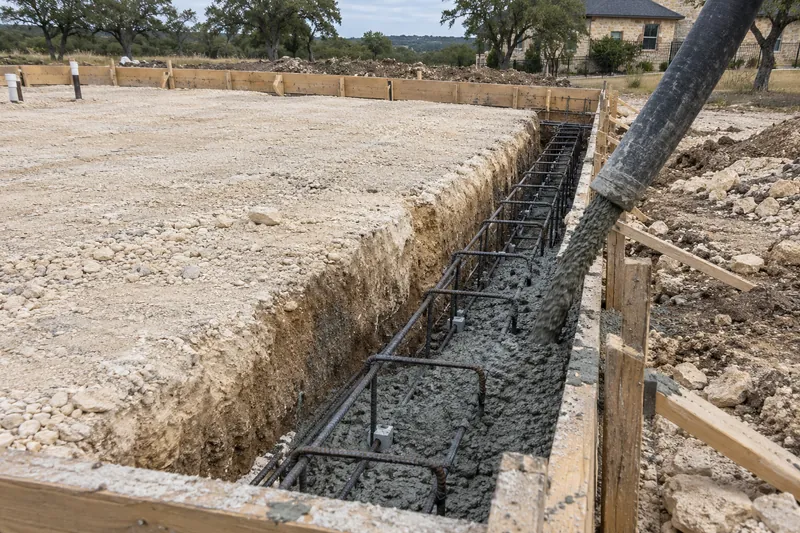 Pump hose placing concrete into a foundation's grade beam trench
