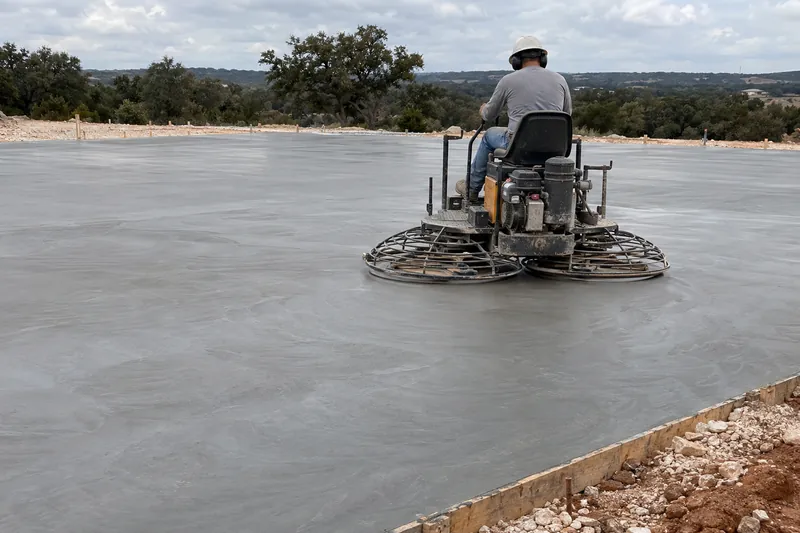 Ride-on power trowel smoothing a large new concrete slab