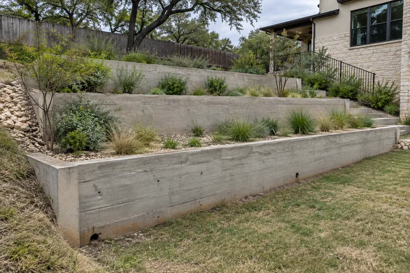 Terraced board-formed concrete retaining walls on a sloping yard